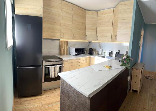 eine Küche mit Holzschränken und einem schwarzen Kühlschrank in der Unterkunft Breathtaking Scenery and Cozy Comfort in Bergen in Bergen