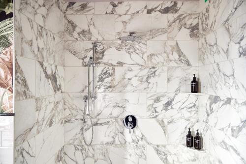 a white marble bathroom with a shower with bottles at Zelda Dearest in Asheville