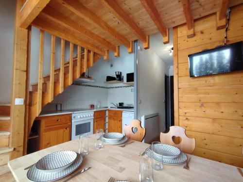 a dining room with a wooden table and a kitchen at Cocon Alpin - Praz de Lys Sommand in Mieussy