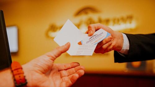 a person handing another person a piece of paper at Howard Johnson La Cañada Hotel & Suites in Córdoba