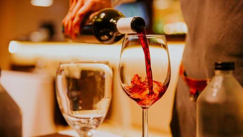 a person pouring red wine into a wine glass at Howard Johnson by Wyndham Córdoba La Cañada in Cordoba