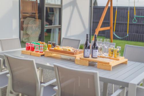 a picnic table with bottles and glasses of wine at New Luxury Home with Games Room and Park Outlook Sleeps 12, 26 mins from CHC airport in Lincoln
