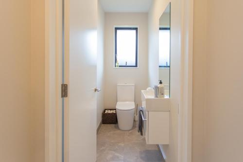a bathroom with a white toilet and a sink at New Luxury Home with Games Room and Park Outlook Sleeps 12, 26 mins from CHC airport in Lincoln