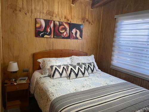 1 dormitorio con 1 cama con 2 almohadas y ventana en Cabaña el Arrayan Futaleufú, en Futaleufú