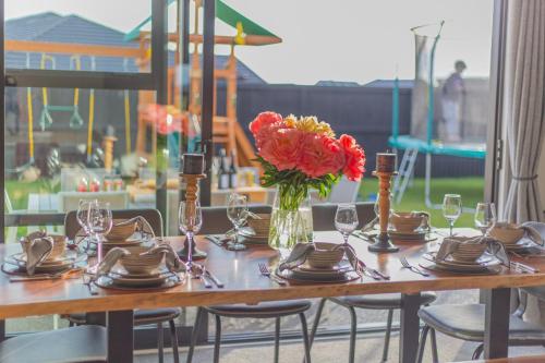 a wooden table with a vase of flowers on it at New Luxury Home with Games Room and Park Outlook Sleeps 12, 26 mins from CHC airport in Lincoln