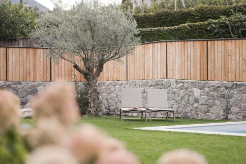a park bench next to a stone wall with a tree at Apartsuites Rosengarten in Lagundo