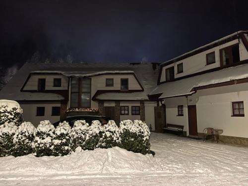 uma casa está coberta de neve à noite em Penzión Hruboš em Habovka