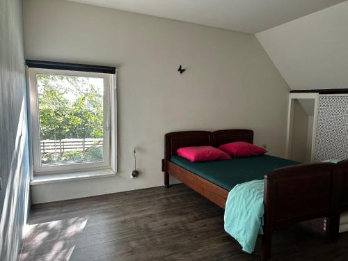 Un dormitorio con una cama con almohadas rojas y una ventana en Moerse rust, en 's-Gravenmoer