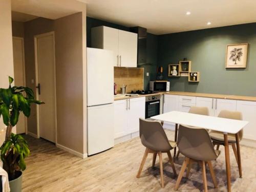 a kitchen with white cabinets and a table and chairs at Maison 4 p. Château de la Loire in Sonzay