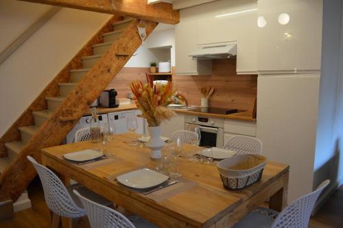 une cuisine avec une table en bois, des chaises et un escalier dans l'établissement Charmant appartement - proche château cité, à Carcassonne