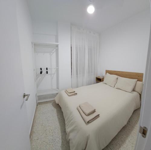 a white bedroom with a large bed with towels on it at Apartamento Gómez in Caravaca de la Cruz