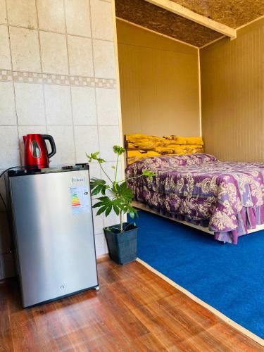 um pequeno quarto com uma cama e um frigorífico em Tiny house em Ancud