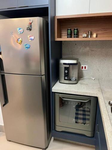 a kitchen with a refrigerator with magnets on it at Condomínio pé na areia, super novo e confortável. in São Sebastião