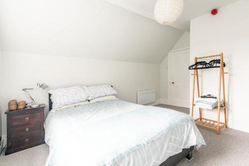 a bedroom with a white bed and a wooden dresser at Radbourne Apartments in Derby