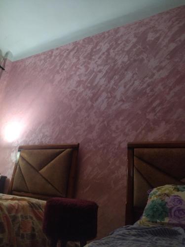 sypialnia z 2 łóżkami i różową ścianą w obiekcie Cité 1 novembre w mieście Khemis Miliana