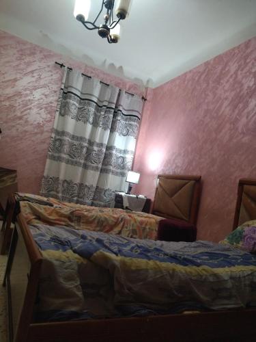 - une chambre avec un lit et un rideau dans l'établissement Cité 1 novembre, à Khemis Miliana