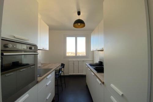 une cuisine avec des placards blancs et une grande fenêtre dans l'établissement Haven of peace in the heart of Caen, à Caen