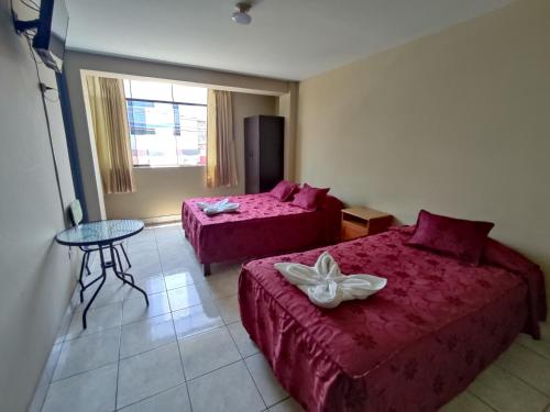 Habitación de hotel con 2 camas y mesa en Hospedaje San Camilo Tacna, en Tacna