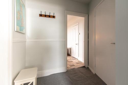 a hallway with a white wall and a white bench at Radbourne Apartments in Derby