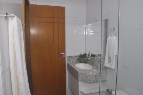 La salle de bains est pourvue d'un lavabo et d'une porte de douche en verre. dans l'établissement Hotel Lafayette, à Itaquaquecetuba