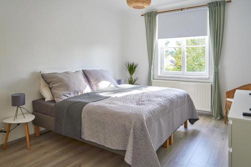 a white bedroom with a bed and a window at revLIVING Apartment Quintus Baden City Center in Baden