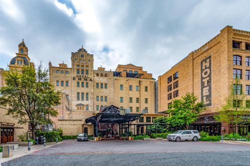 a large building with cars parked in a parking lot at Hotel Emma at Pearl on the Riverwalk in San Antonio