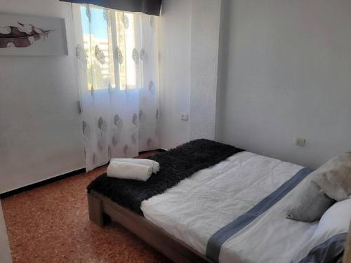 a bed in a room with a window and a bedskirtspectspectspectspects at Amplio apartamento in Puebla de Farnals