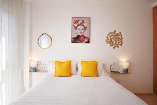 1 dormitorio con cama blanca y almohadas amarillas en Apartamento dúplex Catalunya, en Sant Antoni de Calonge