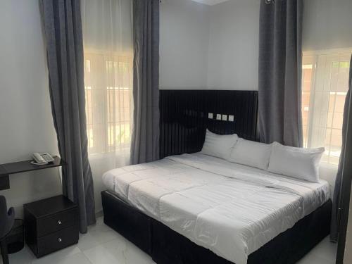 1 dormitorio con 1 cama con sábanas y almohadas blancas en Bott Extended Stay, en Abuja