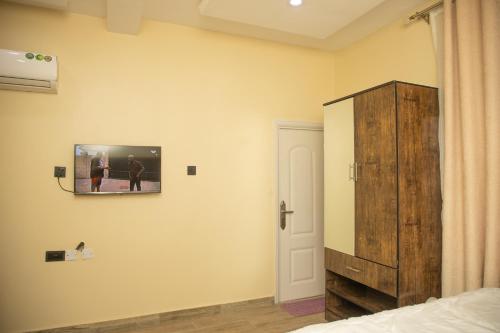 um quarto com uma televisão na parede ao lado de uma cama em Bott Extended Stay em Abuja