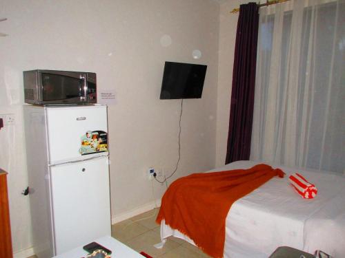 a small bedroom with a refrigerator and a tv on the wall at Happy Homes BnB in Nairobi