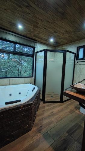 a large bathroom with a large tub and windows at Cabaña Luna Encantada in Mazamitla