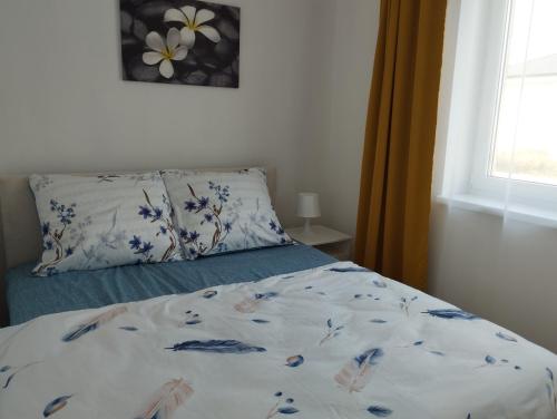 a bed with a floral comforter and a pillow at New apartman Sali in Galanta