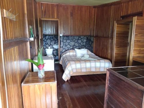 a small bedroom with a bed and a table at Hotel Green Mountain turrialba in Turrialba