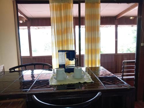 a table with two cups and a coffee maker on it at Hotel Green Mountain in Turrialba