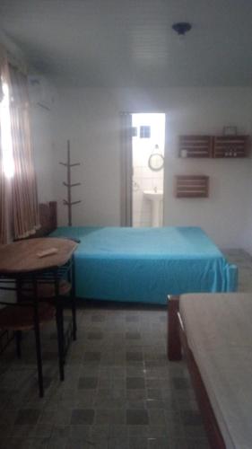 Un dormitorio con una cama azul y una mesa en Villa Tamandaré en Tamandaré