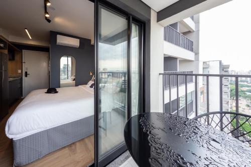 ein Schlafzimmer mit einem Bett und einem Balkon in der Unterkunft Charlie Nik Vila Mariana in São Paulo