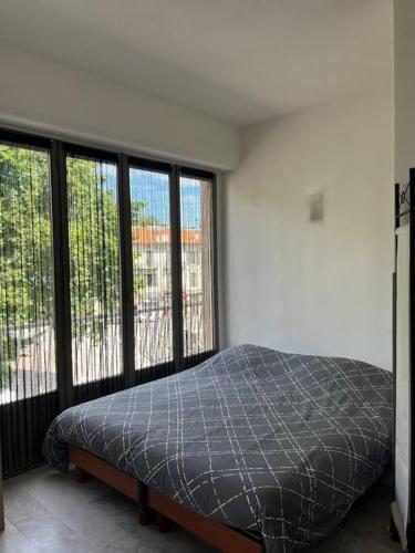 a bedroom with a bed and large windows at Grand studio Nice centre in Nice