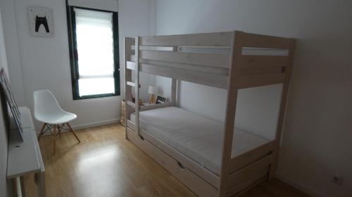 Letto a castello in camera con sedia e finestra di VILLANUA ACOGEDOR PISO CON GARAJE, PADEL Y PISCINA a Villanúa