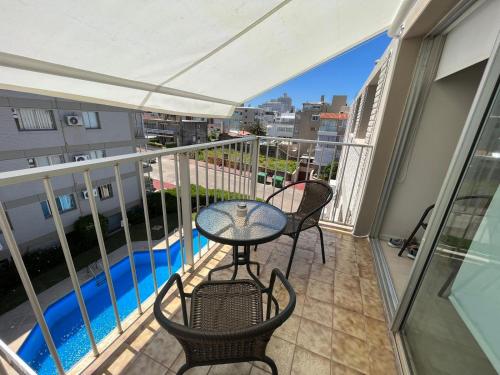 un balcone con tavolo e sedie e una piscina di Apartamento playa el Emir a Punta del Este