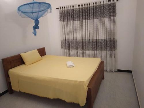 Un pequeño dormitorio con una cama con sábanas amarillas y una ventana en White House, en Weligama