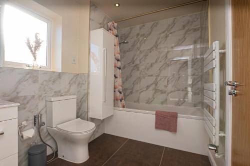 a bathroom with a toilet and a bath tub at Central, Large 4 double bedroom house in Leicester