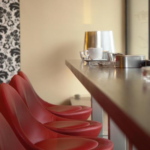 a row of red chairs sitting at a bar at Smartcity Designhotel in Hannover