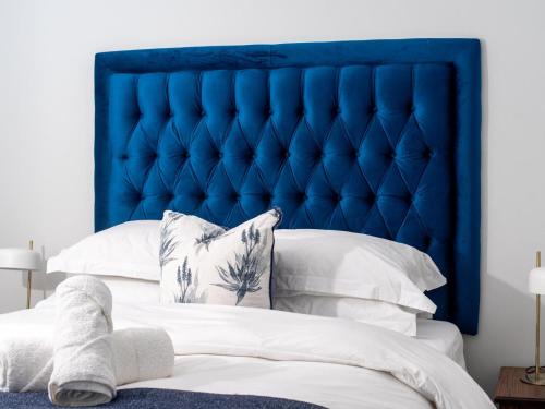 a bed with a blue headboard and white pillows at Executive apartment, Ellipse in Midrand