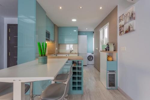 una cocina con armarios azules y una mesa y sillas blancas. en Céntrico apartamento Templo Quevedo Gran parking gratis, en Granada
