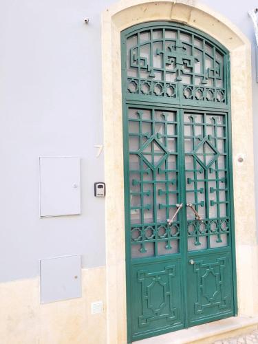 zielone drzwi na boku budynku w obiekcie Penedo Grande suítes t1 w mieście São Bartolomeu de Messines