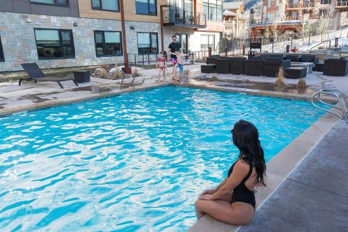 una donna seduta sul bordo di una piscina di Lift by All Seasons Resort Lodging a Park City