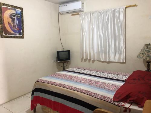 1 dormitorio con 1 cama, TV y ventana en Hospedaje Maluli suit 4, en Santa Elena