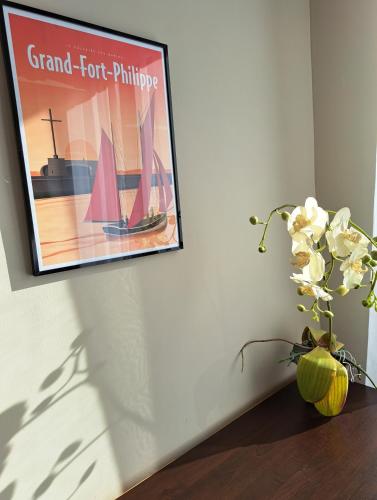 une photo accrochée sur un mur avec un vase de fleurs dans l'établissement Au gîte de la Matelote, à Grand-Fort-Philippe