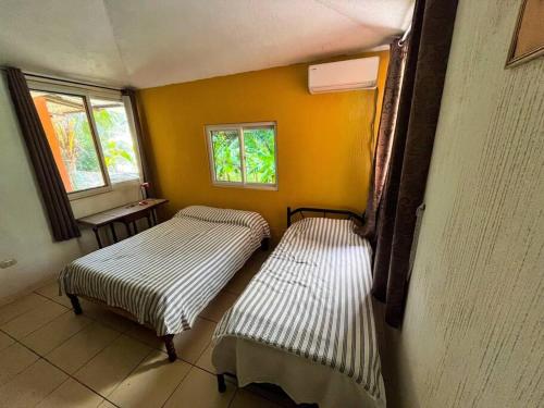 Duas camas num quarto com paredes amarelas e janelas em El encanto tropical, a minutos del IRTRA em Ajaxá